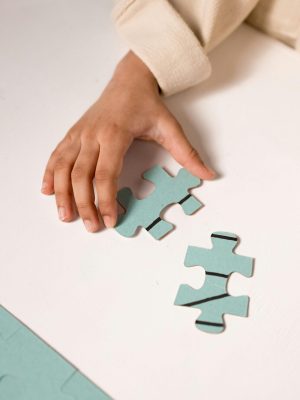A child's hand in focus, solving a pastel blue puzzle, illustrating focus and learning.